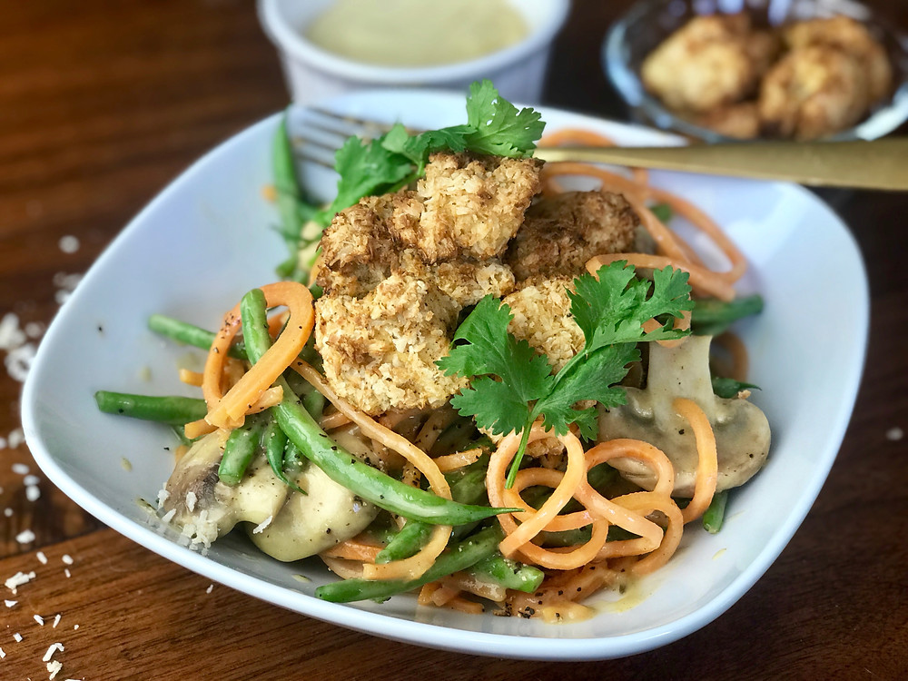 Crispy coconut tofu bites atop vibrant mango curry with spiralized sweet potato noodles, green beans, and mushrooms