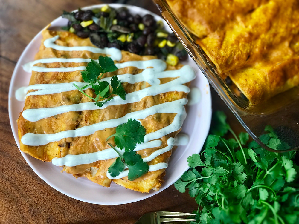 Vegan enchiladas topped with creamy cashew sauce and cilantro